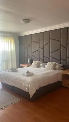 a bedroom with a large bed with a large headboard at The Other House - Cape Town in Cape Town