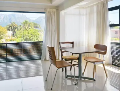 a table and chairs in a room with a large window at The Other House - Cape Town in Cape Town