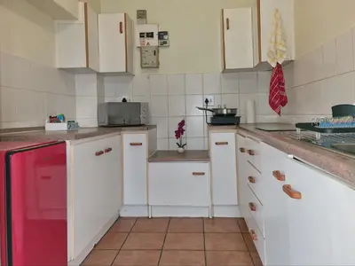 a kitchen with white cabinets and a red refrigerator at Loft Cottage, sleeps 2. Central and Cozy! in Cape Town