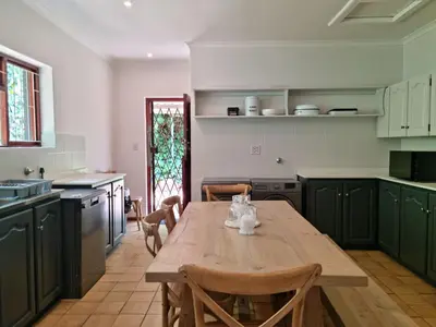 a kitchen with a wooden table and green cabinets at '79 Protea' Charming self-catering Home, sleeps 6 with Sea Views in Gordonʼs Bay