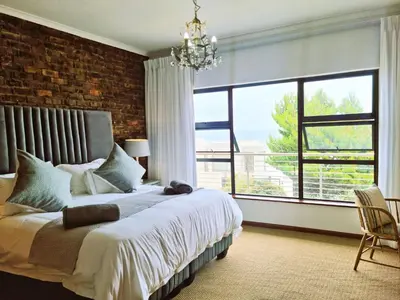 a bedroom with a large bed and a brick wall at '79 Protea' Charming self-catering Home, sleeps 6 with Sea Views in Gordonʼs Bay