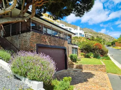a brick house with a garage in the yard at '79 Protea' Charming self-catering Home, sleeps 6 with Sea Views in Gordonʼs Bay
