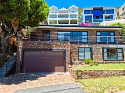 a brick house with a garage in front of it at '79 Protea' Charming self-catering Home, sleeps 6 with Sea Views in Gordonʼs Bay
