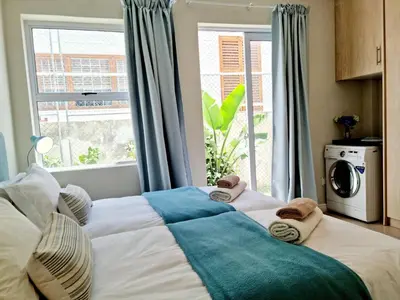 a bedroom with a large bed with a window at Beach Apartment on Bikini Beach - sleeps 4 in 2 Ensuite Bedrooms in Cape Town