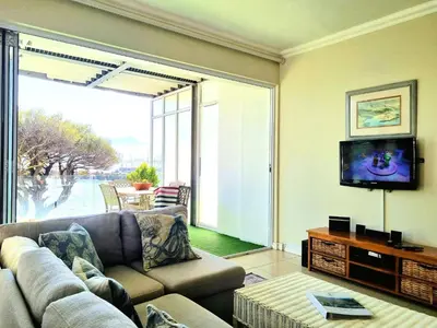 a living room with a couch and a tv at Beach Apartment on Bikini Beach - sleeps 4 in 2 Ensuite Bedrooms in Cape Town