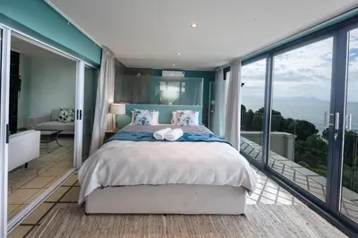 a bedroom with a large bed and large windows at 'Ocean Views', Modern, Spacious Home, 3 En-suite Bedrooms in Cape Town