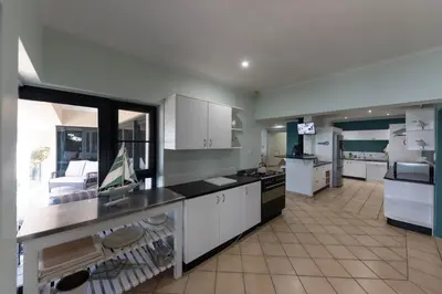 a large kitchen with white cabinets and a large window at 'Ocean Views', Modern, Spacious Home, 3 En-suite Bedrooms in Cape Town