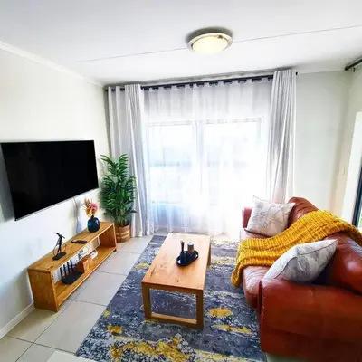 a living room with a couch and a flat screen tv at 1d - Serene Retreat of Parklands in Cape Town