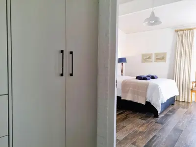 a bedroom with a bed and a room with a closet at '75 Protea' 4 Bedroom Holiday Home for 8 with Private Pool and Ocean Views in Cape Town