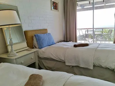 a bedroom with two beds and a mirror and a window at '75 Protea' 4 Bedroom Holiday Home for 8 with Private Pool and Ocean Views in Cape Town