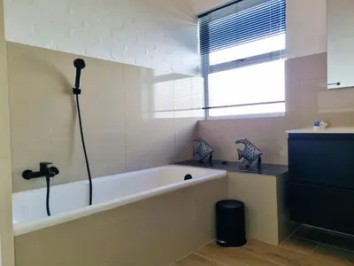 a bath tub in a bathroom with a window at '75 Protea' 4 Bedroom Holiday Home for 8 with Private Pool and Ocean Views in Cape Town