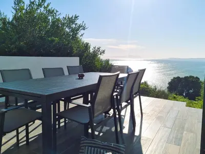 a table and chairs on a deck with the ocean at '75 Protea' 4 Bedroom Holiday Home for 8 with Private Pool and Ocean Views in Cape Town