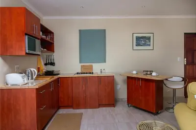 a kitchen with wooden cabinets and a counter top at Le Gaulois Luxury Apartments, sleeps 2, Sea Views in Gordonʼs Bay