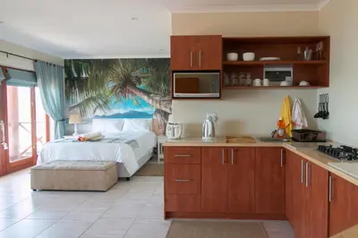 a kitchen with a bed with a palm tree mural on the wall at Le Gaulois Luxury Apartments, sleeps 2, Sea Views in Gordonʼs Bay