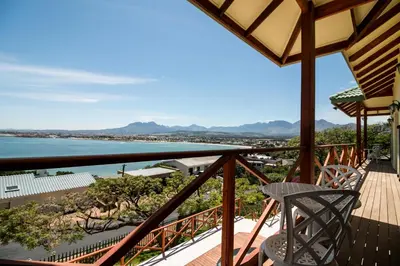 a balcony with a chair and a view of the water at Le Gaulois Luxury Apartments, sleeps 2, Sea Views in Gordonʼs Bay