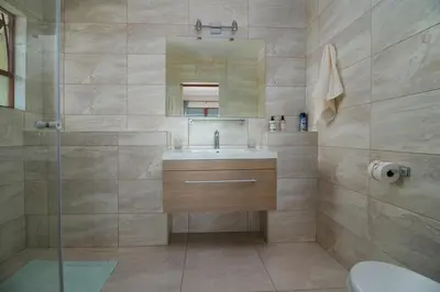 a bathroom with a sink and a shower with a mirror at Le Gaulois Luxury Apartments, sleeps 2, Sea Views in Gordonʼs Bay