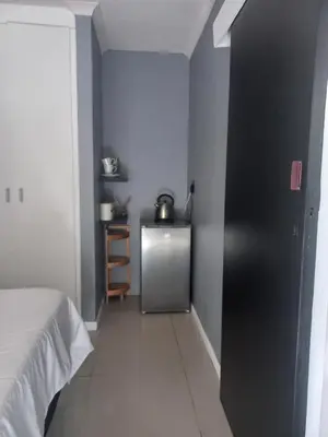 a room with a bed and a refrigerator at Freys 1 in Cape Town