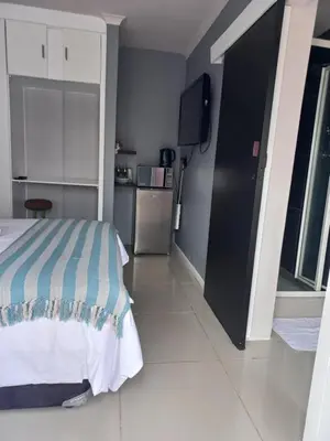 a bedroom with a bed and a small kitchen at Freys 1 in Cape Town