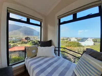a bedroom with a bed and a large window at Peaceful Seaside Cottage, Betty's Bay Accommodation in Clareport