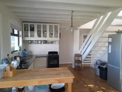 a kitchen with a wooden table and a staircase at Peaceful Seaside Cottage, Betty's Bay Accommodation in Clareport