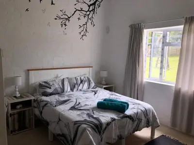 a bedroom with a bed and a window at Rustica in Onrus close to the beach in Hermanus