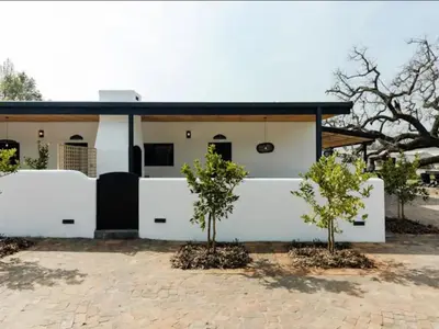a white house with two trees in front of it at Nooitgedacht Guest Farm Cottages in Kayamnandi