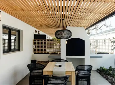 a patio with a wooden ceiling and a table and chairs at Nooitgedacht Guest Farm Cottages in Kayamnandi