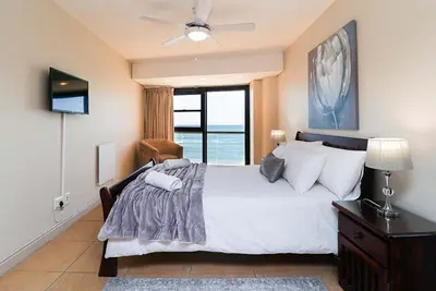 a bedroom with a large white bed with a window at 302 Ocean View in Strand