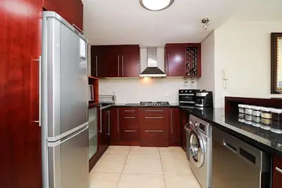 a kitchen with wooden cabinets and a stainless steel refrigerator at 302 Ocean View in Strand