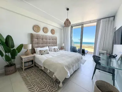 a bedroom with a bed with a view of the ocean at Happy Dolphin - Luxury 3BR Sea View Apartment in Cape Town