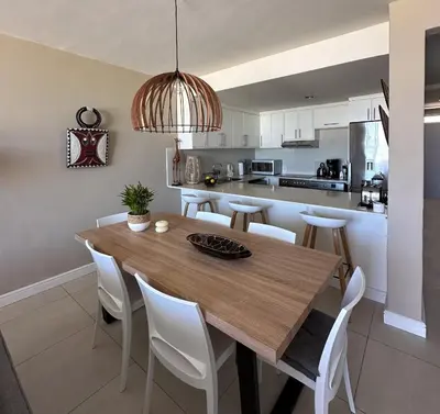 a kitchen and dining room with a wooden table and chairs at Happy Dolphin - Luxury 3BR Sea View Apartment in Cape Town