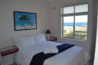 a bedroom with a bed with a view of the beach at Simplicity with an ocean view 200 in Hermanus