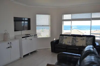 a living room with a black couch and a television at Simplicity with an ocean view 200 in Hermanus