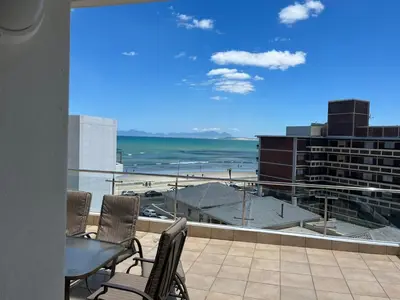 a balcony with a table and chairs and a view of the beach at 502 Hibernian Towers in Cape Town