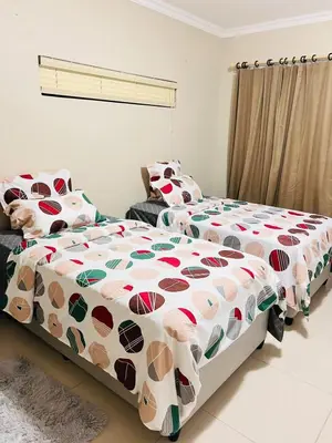 a bedroom with two beds with a comforter at Pemba's residence in Cape Town