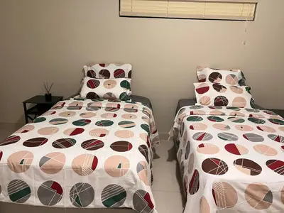 a bedroom with two beds with colorful pillows at Pemba's residence in Cape Town