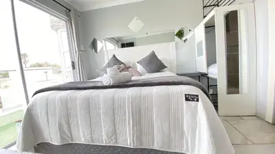 a bedroom with a large bed with white sheets and pillows at Kwaaamiii in Cape Town