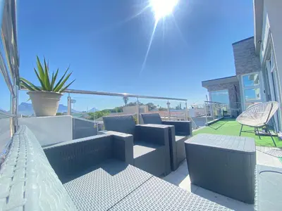 a balcony with couches and chairs on a house at Kwaaamiii in Cape Town