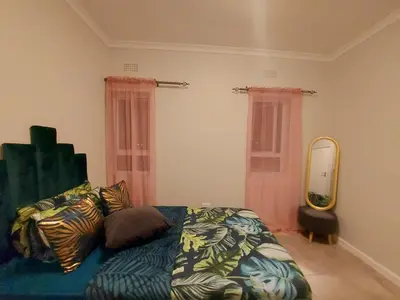 a bedroom with a bed and a large mirror at Serenity on the Atlantic seaboard house shared in Cape Town