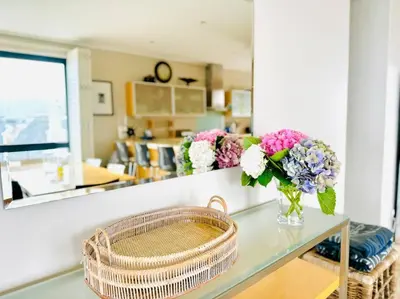 a room with a table with a vase of flowers on it at 74 on Marine - Apartment 303 in Hermanus