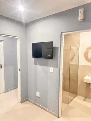 a bathroom with a flat screen tv on the wall at Malaika Guest House in Cape Town