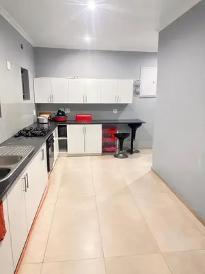 a kitchen with white cabinets and a table in it at Malaika Guest House in Cape Town