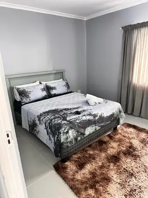 a bedroom with a bed and a rug at Malaika Guest House in Cape Town