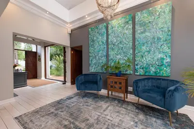 a living room with two blue chairs and a painting on the wall at Banhoek Lodge in Stellenbosch