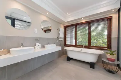 a bathroom with two sinks and two mirrors at Banhoek Lodge in Stellenbosch