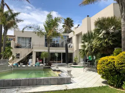 a house with a swimming pool and palm trees at Self Catering Guest House in Cape Town