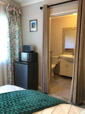 a bedroom with a bed and a sink and a mirror at Self Catering Guest House in Cape Town