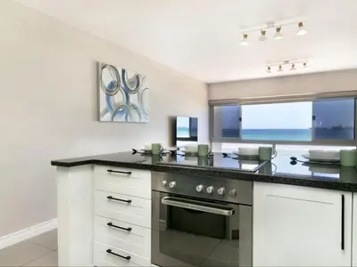 a kitchen with white cabinets and a stove top oven at Zeezicht 204 Bloubergstrand in Bloubergstrand