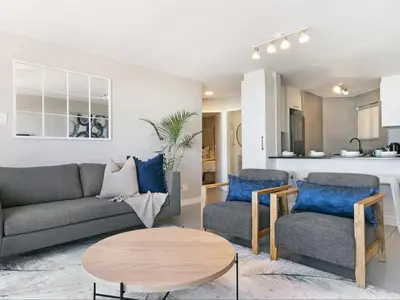 a living room with a couch and two chairs and a table at Zeezicht 204 Bloubergstrand in Bloubergstrand