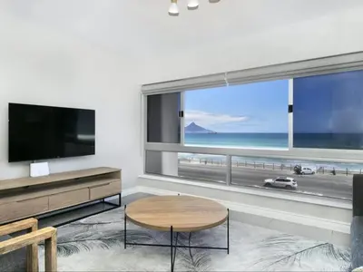 a living room with a large window with a view of the beach at Zeezicht 204 Bloubergstrand in Bloubergstrand